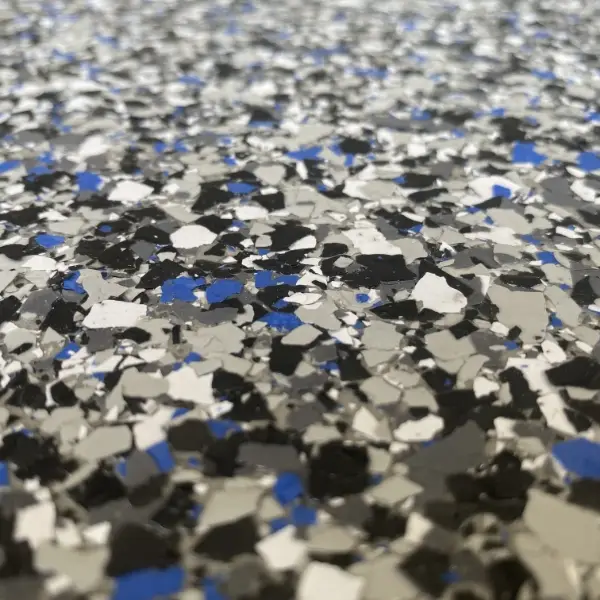 Close-up of a speckled surface featuring black, gray, white, and blue flakes, resembling a textured floor or countertop with a smooth finish.