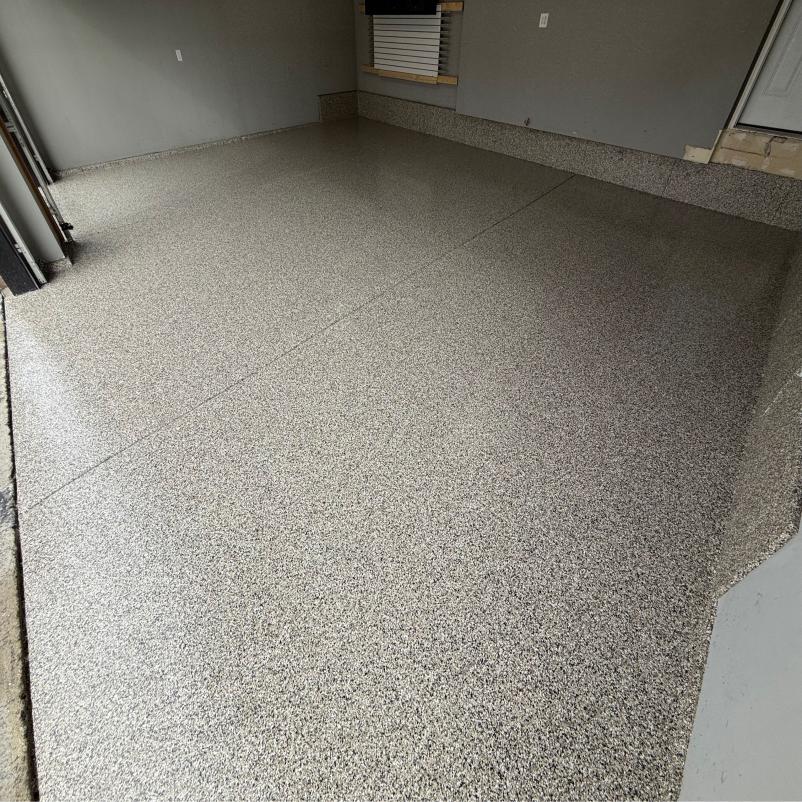 Clean garage interior with smooth, polished epoxy floor, grey walls, and a window with blinds. No furniture or visible objects present.